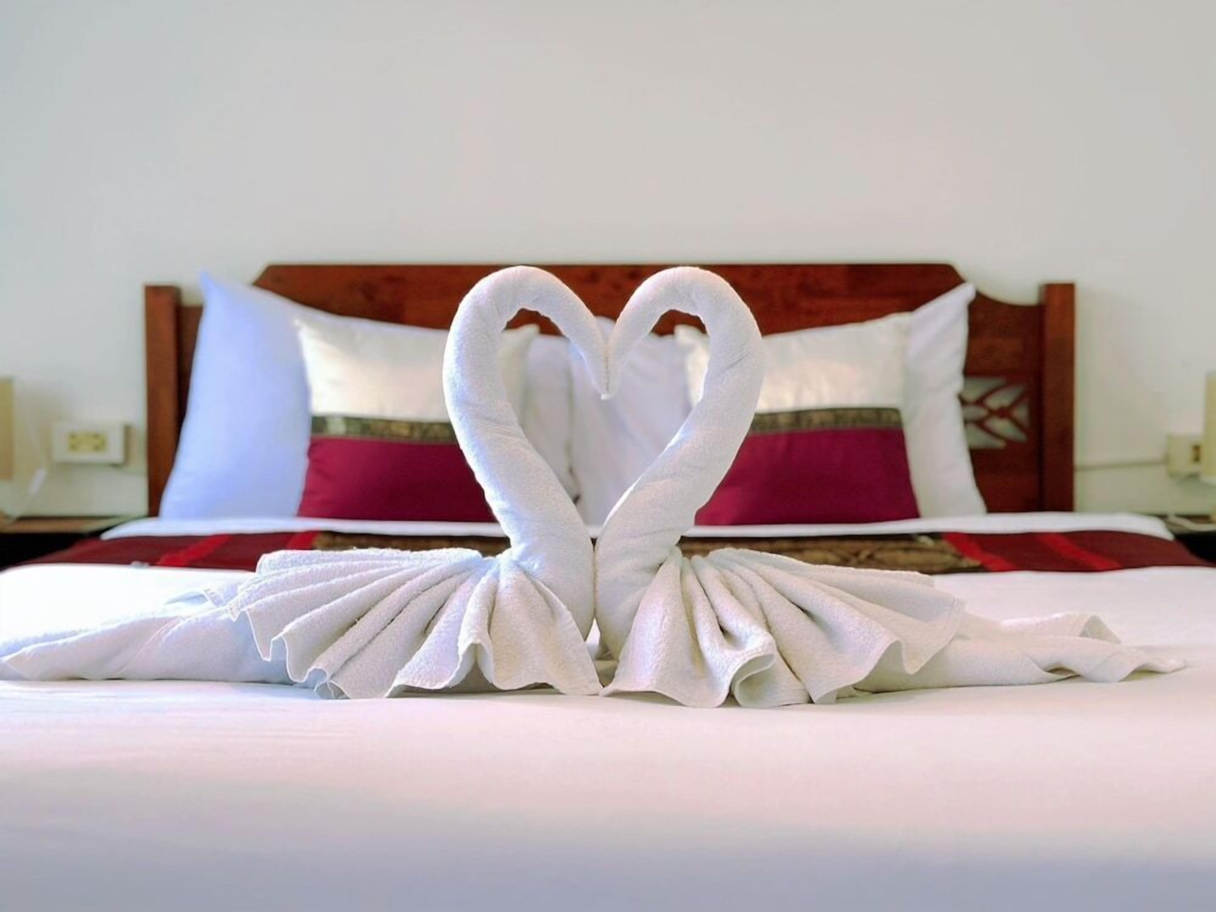 A bed with a white bedspread and a red and white pillow.