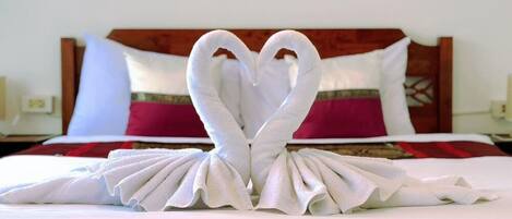 A bed with a white bedspread and a red and white pillow.
