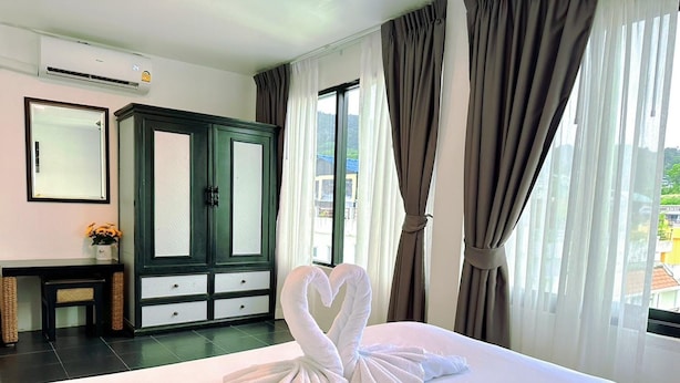 A hotel room with a bed, a wardrobe, a mirror, and a window with curtains. - Hotel Baya Patong Beach (Patong)