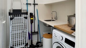 Ein kleiner Hauswirtschaftsraum mit Waschmaschine, Wäscheständer und Spüle.