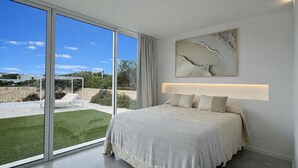 Ein Schlafzimmer mit einem großen Bett, Blick auf einen Garten und modernem Design.
