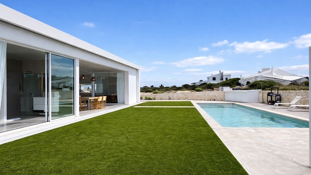 Ein modernes Haus mit Swimmingpool, gepflegtem Rasen und einer Terrassenanlage.