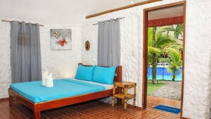A single-bed room with a wooden frame, a blue bedspread, and grey curtains. - Panglao Chocolate Hills Resort (Panglao)