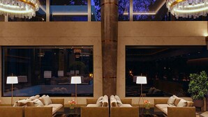 Un hall d’entrée avec des canapés, des lampes et une grande fenêtre donnant sur un espace piscine.