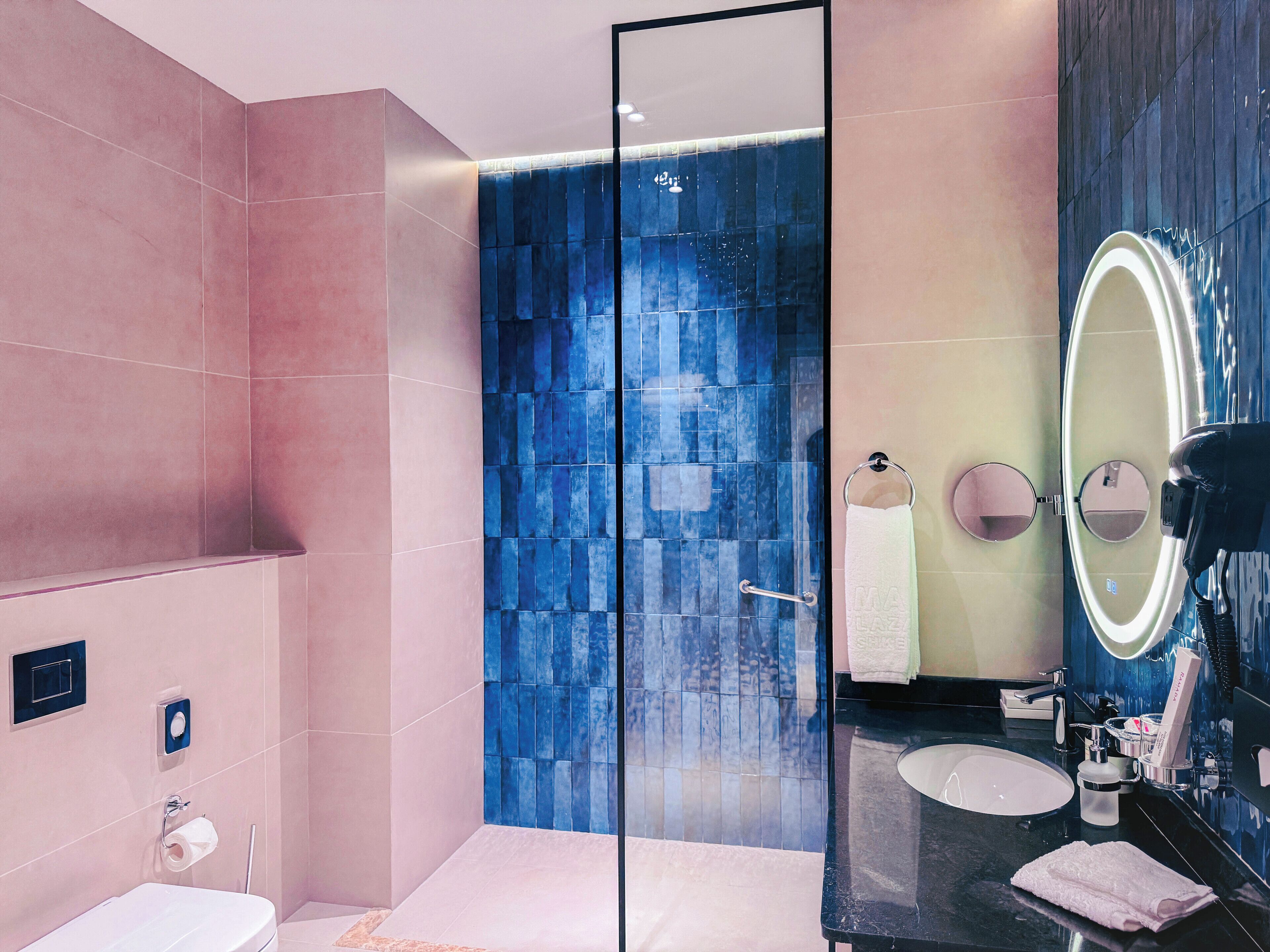 A modern bathroom with a glass-enclosed shower, a vanity with a mirror, and a sink.