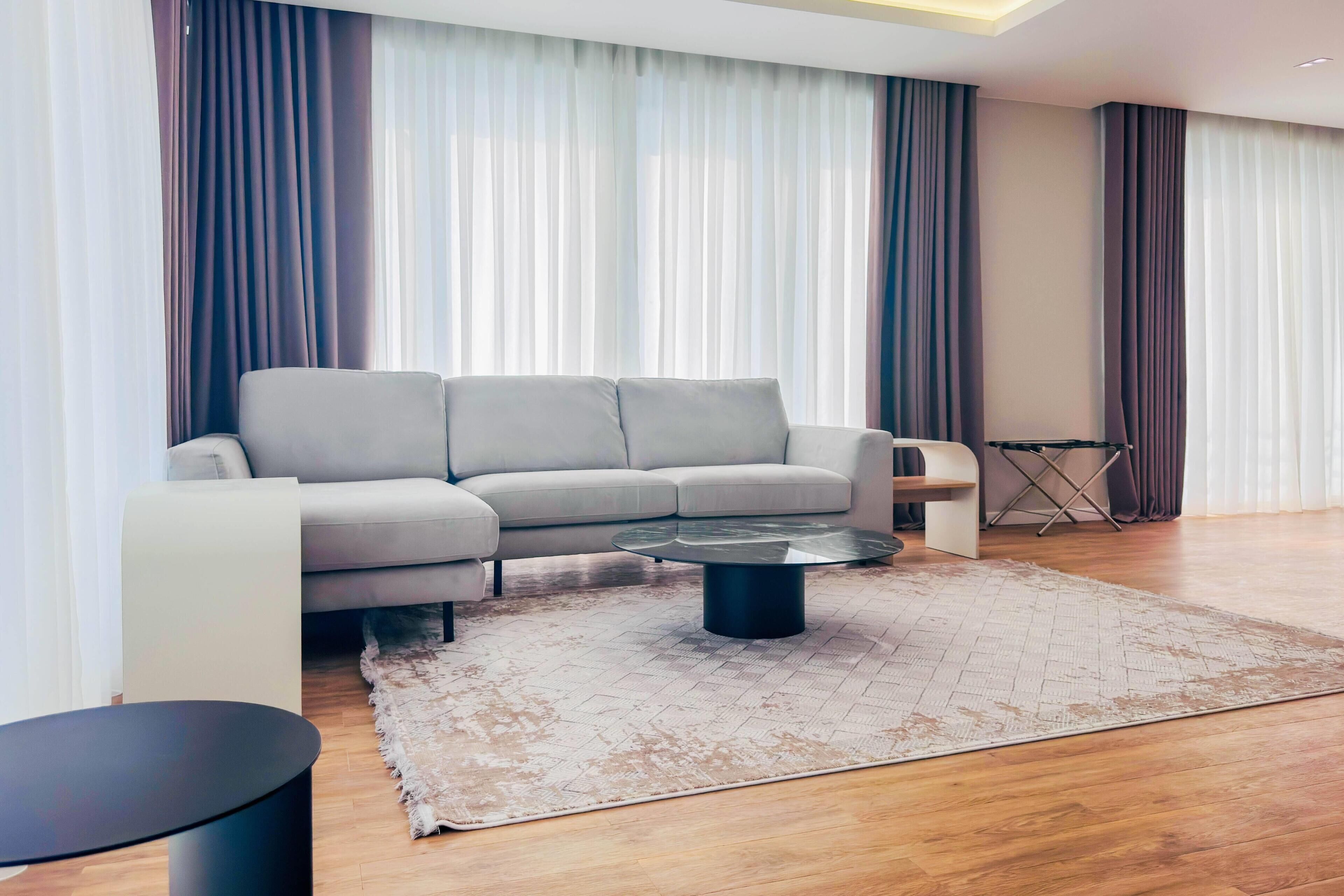 A modern living room with a grey sofa, a round coffee table, and a patterned rug.