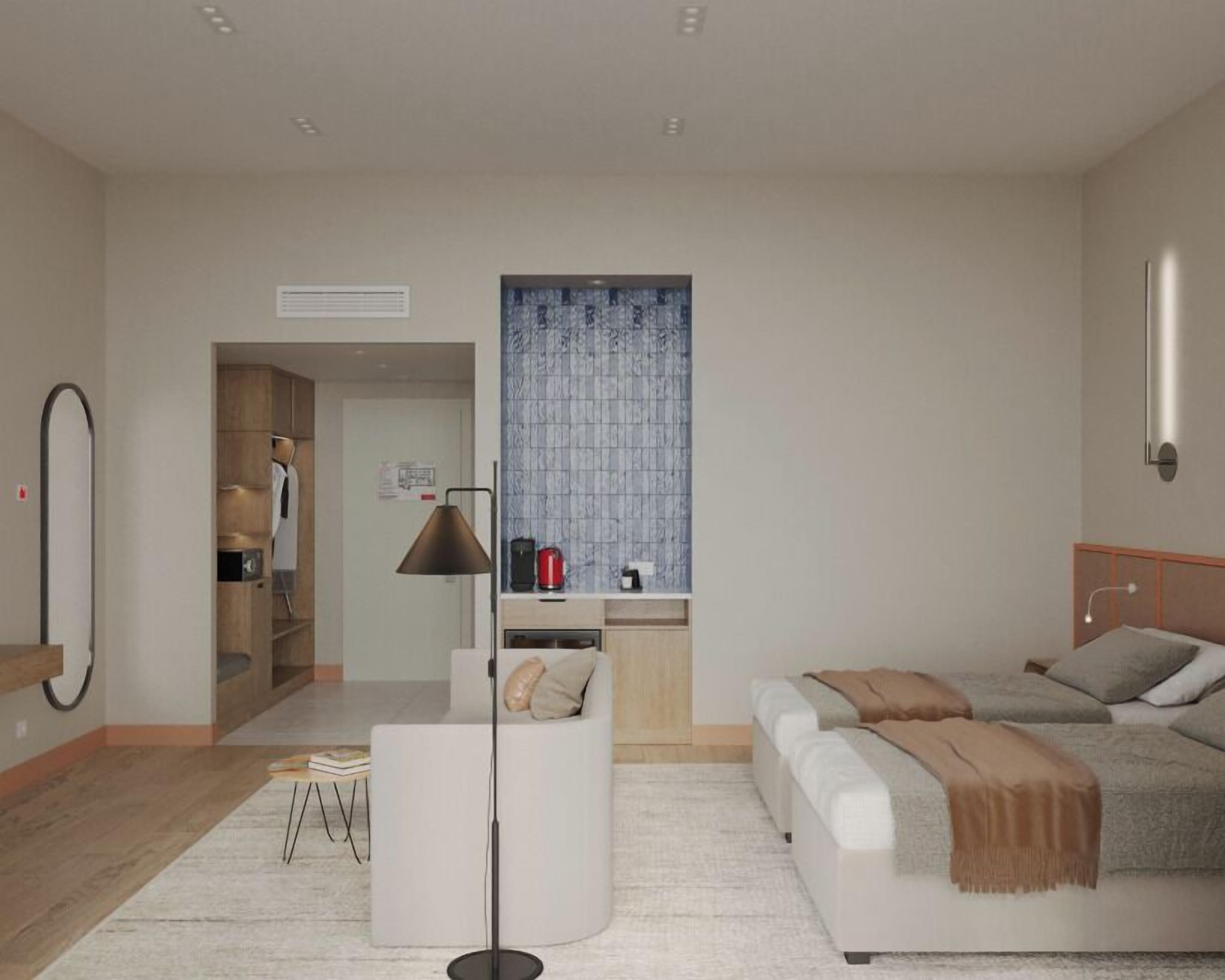 Une chambre moderne équipée d’un canapé-lit, d’une lampe sur pied, d’une machine à café et d’une armoire.