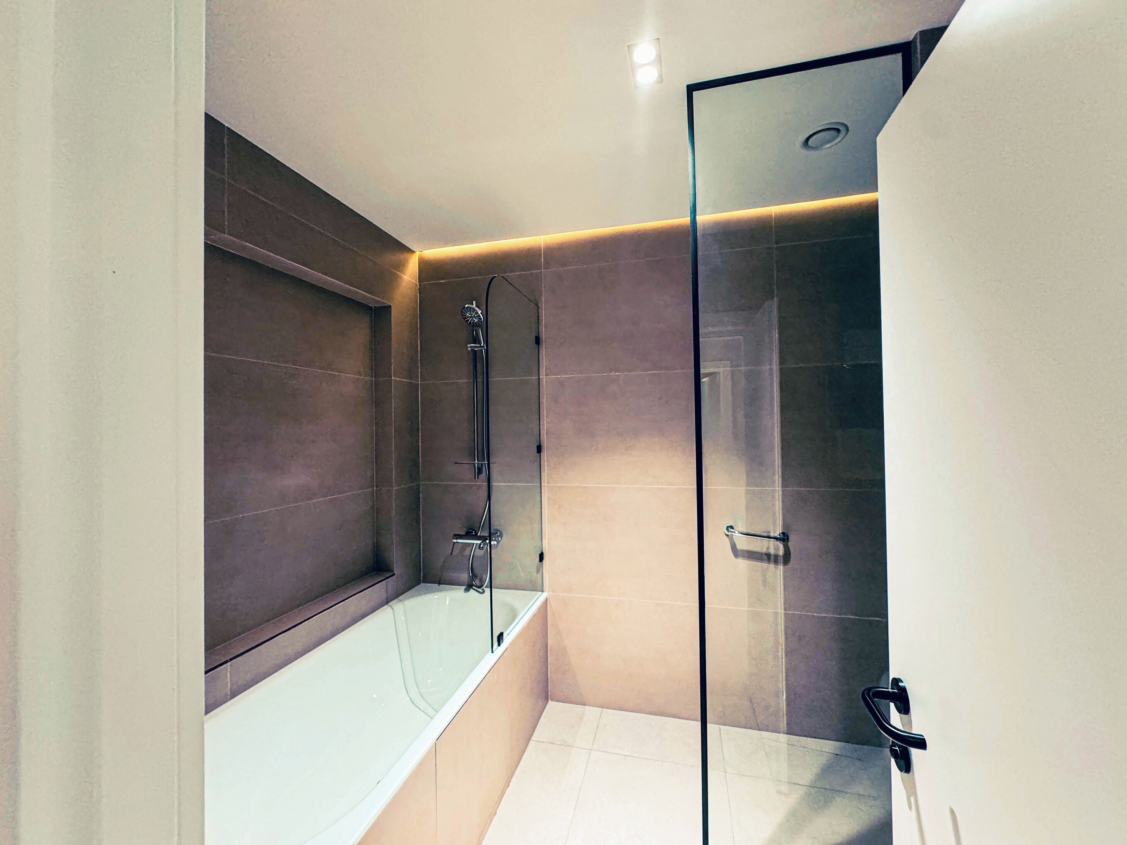 A modern bathroom with a glass-enclosed shower, a bathtub, and a vanity with a mirror.