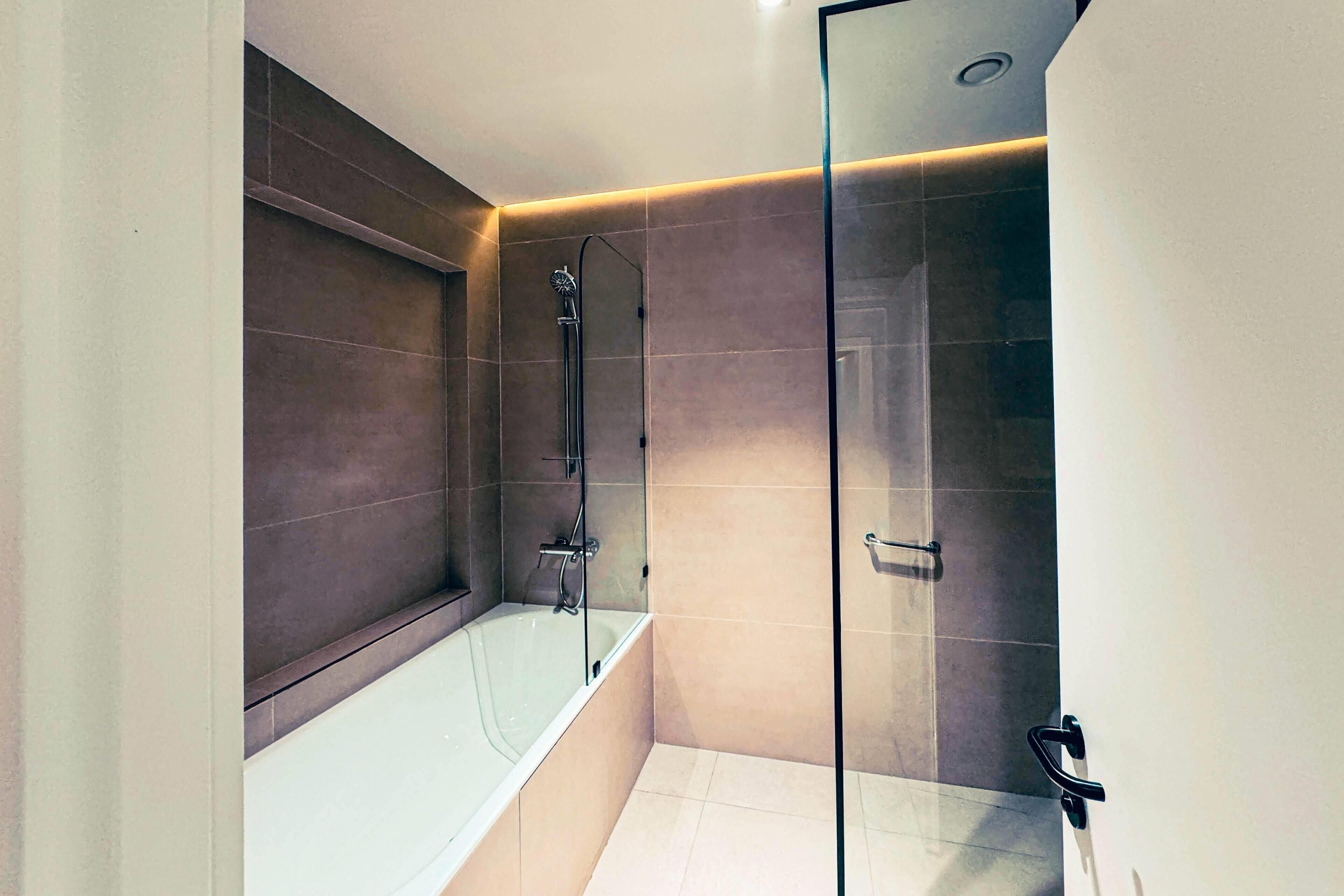 Un baño moderno con bañera, ducha y cabina de ducha acristalada.