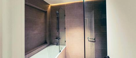 Un baño moderno con bañera, ducha y cabina de ducha acristalada.