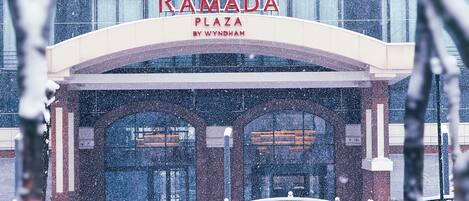 A snow-covered entrance to Ramada Plaza by Wyndham with a modern architectural design.