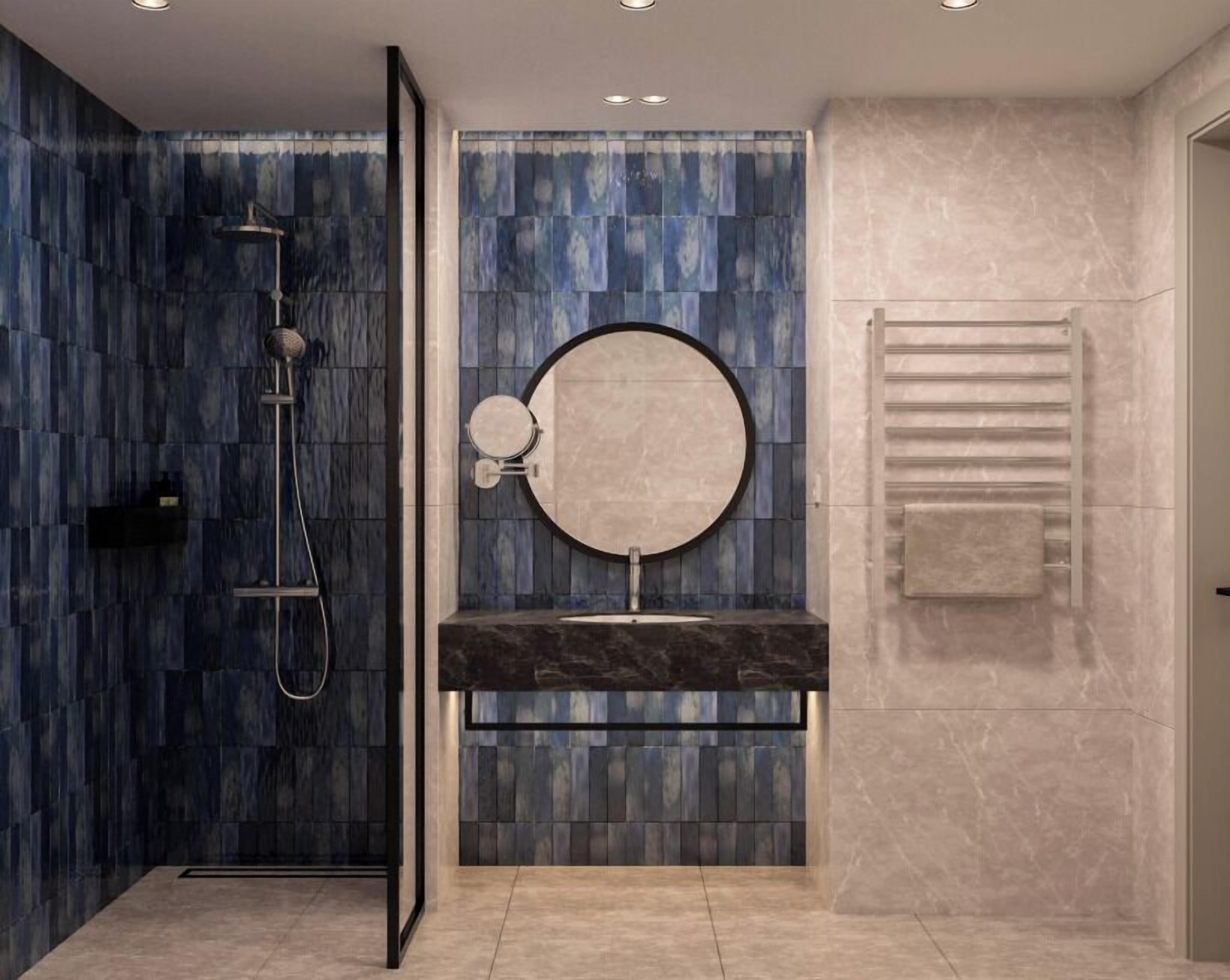 A modern bathroom with a blue-tiled shower, a round mirror, and a marble sink.