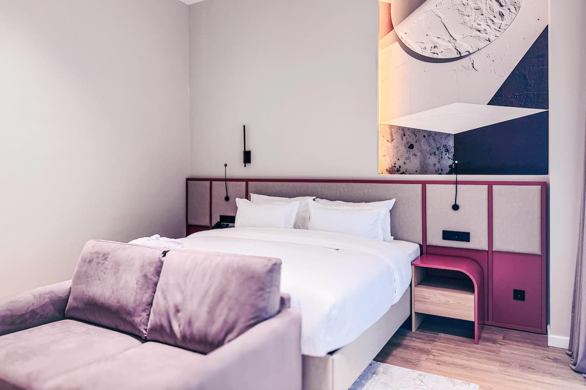 A modern bedroom with a large bed, a bedside table, and a built-in bench.