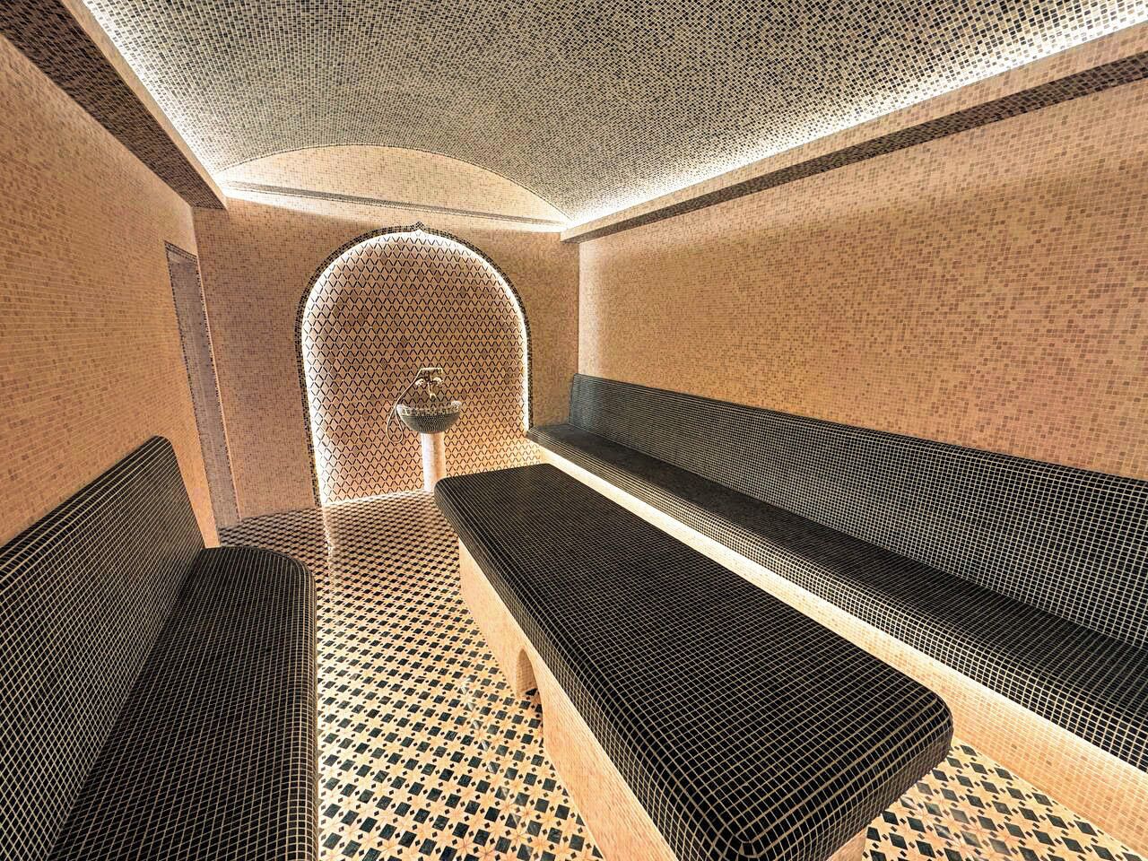 A room with a patterned floor, a bench, and a wall with a geometric design.