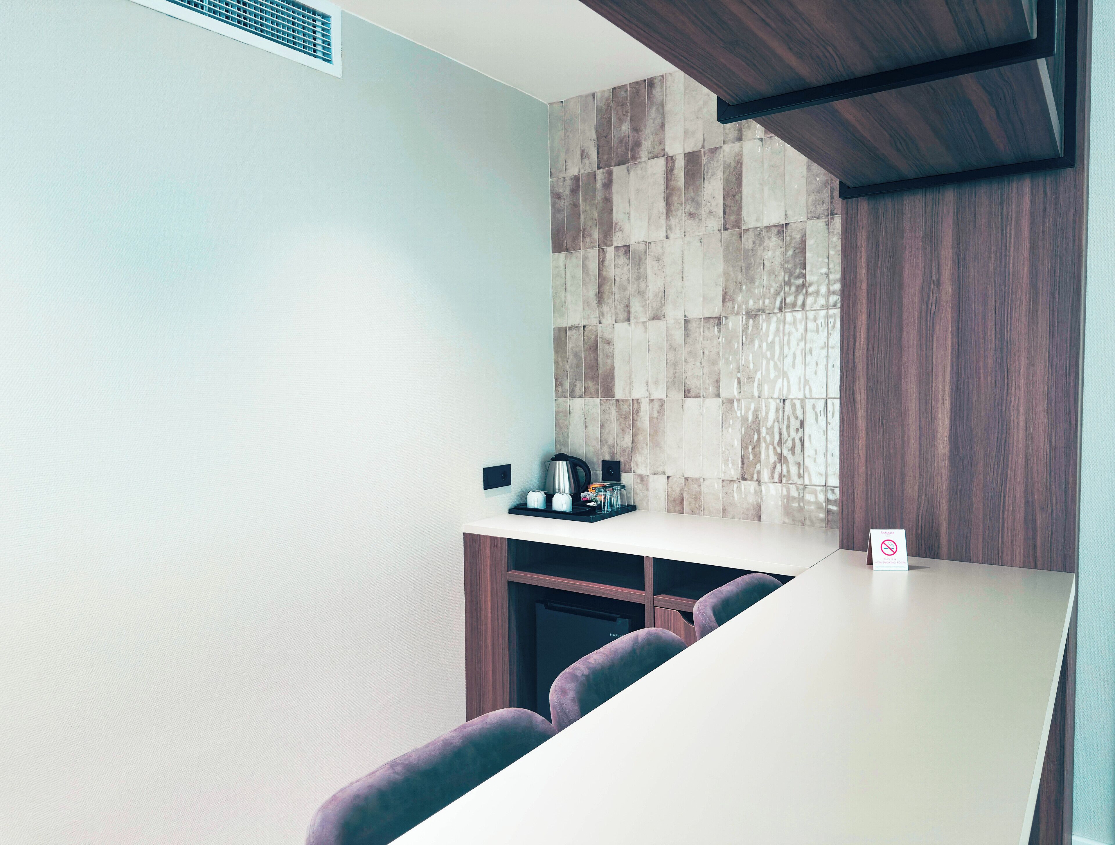 A modern kitchen with a white countertop, a built-in stove, and a wall-mounted coffee maker.