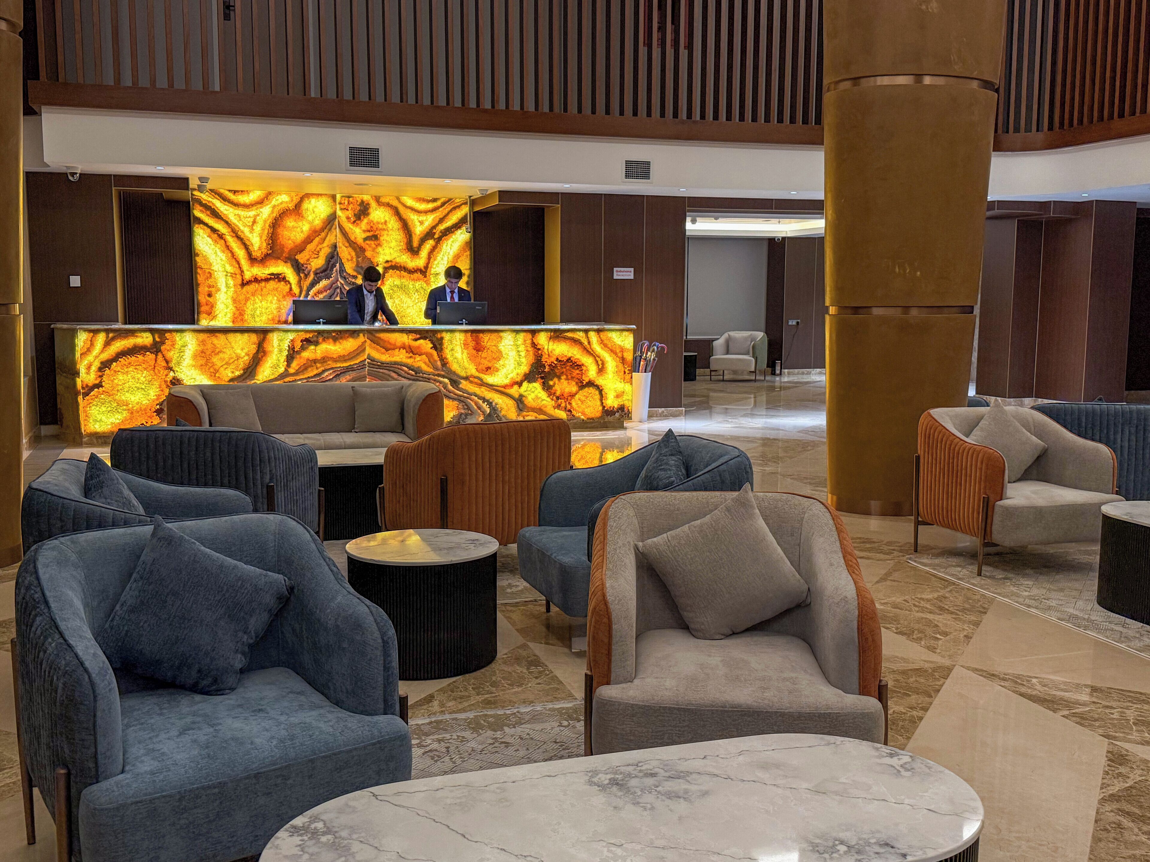 A lobby with seating areas, a reception desk, and a large pillar.