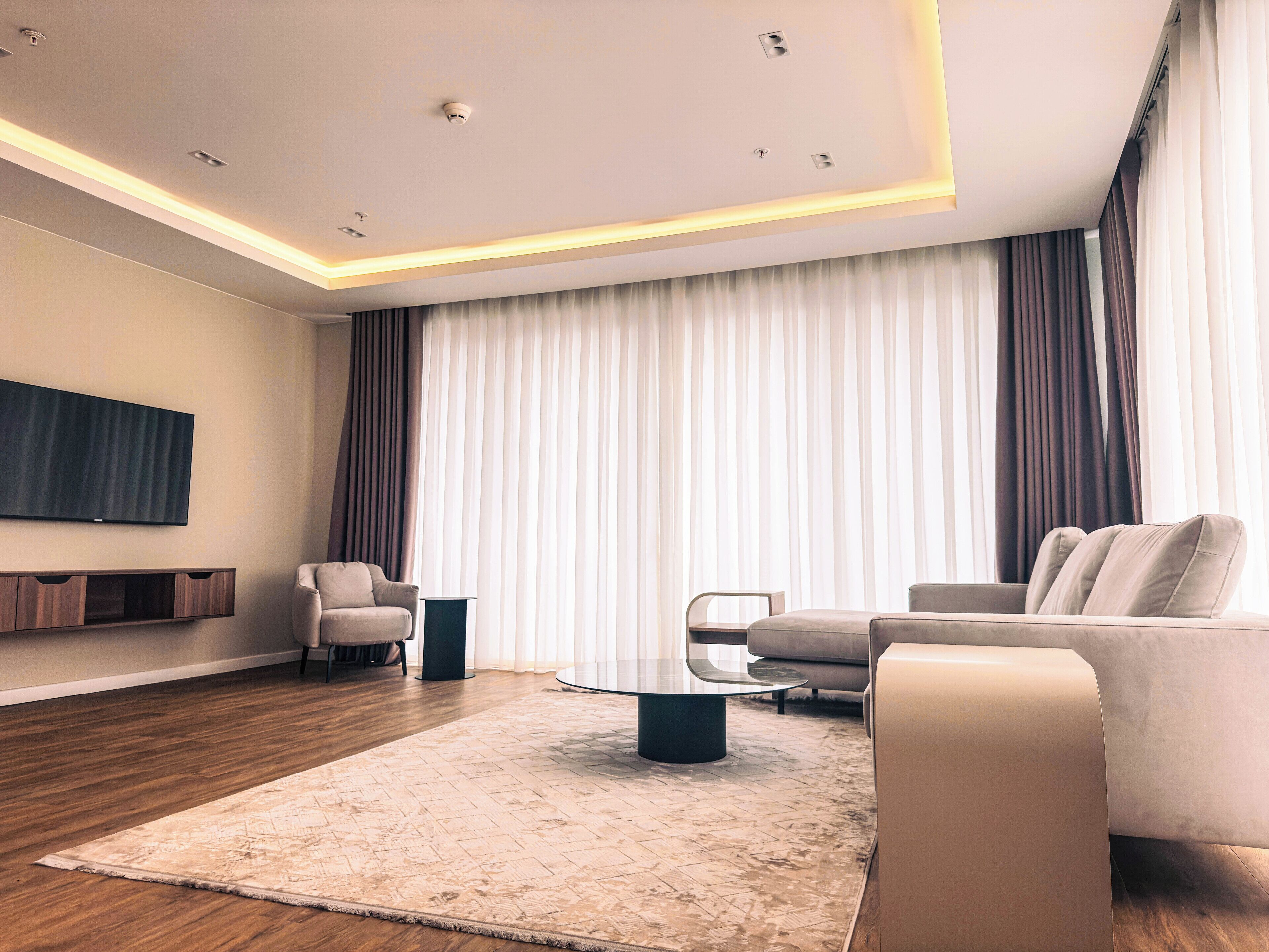 A modern living room with a sofa, coffee table, and a flat-screen TV mounted on the wall.