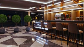 Un espace bar moderne avec un sol à carreaux, des tabourets de bar et des luminaires suspendus.