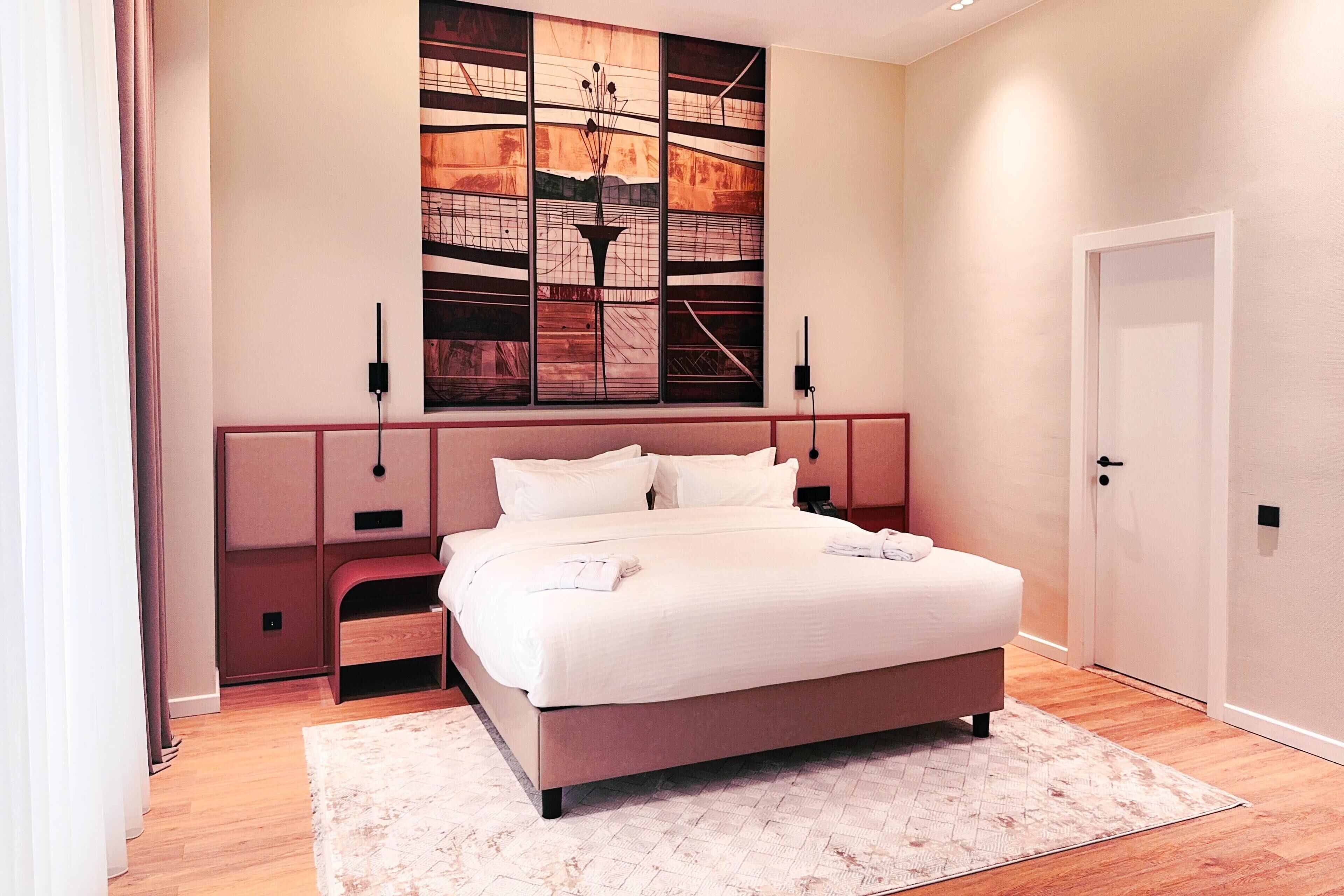 A modern bedroom with a large bed, a decorative wall piece, and a door.
