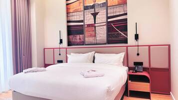 A modern hotel room with a large bed, a nightstand, a telephone, and a wall art piece.