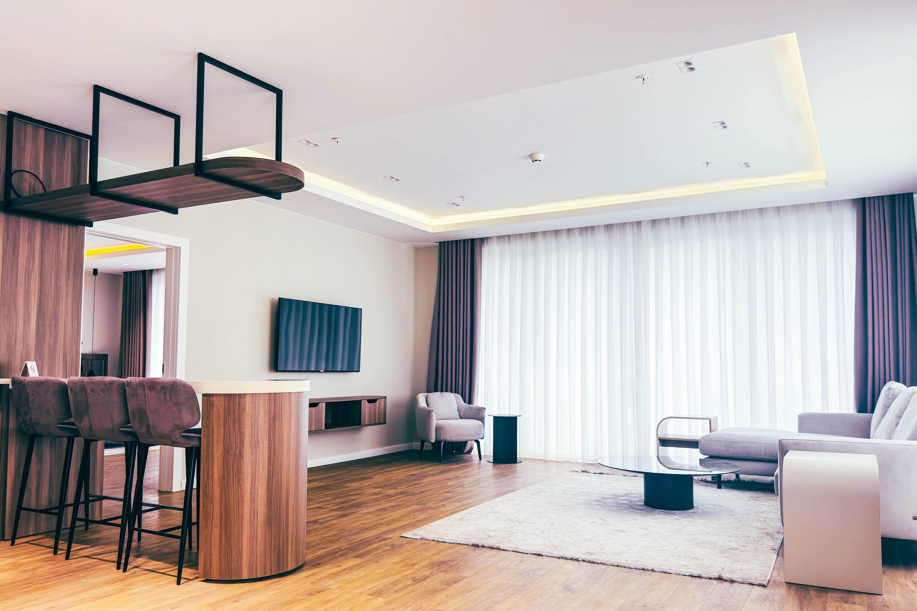 Una sala moderna con piso de madera, una mesa redonda de centro, un sofá y un televisor montado en la pared.