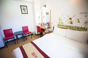 A hotel room with a bed, two red chairs, a desk with a mirror, and a wall with windmill decorations. - Li Qing Hotel (Kaohsiung)