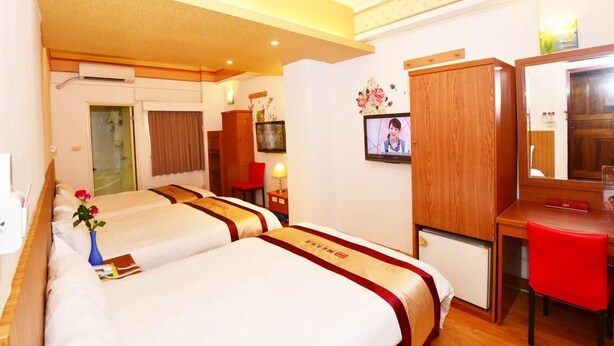 A hotel room with two beds, a desk, a mirror, a TV, and a bathroom visible through an open door. - Nice Hotel (Kaohsiung)