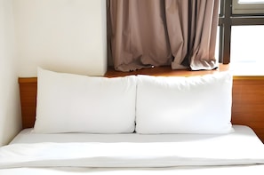 A neatly made bed with white bedding and a wooden headboard. - Li Qing Hotel (Kaohsiung)