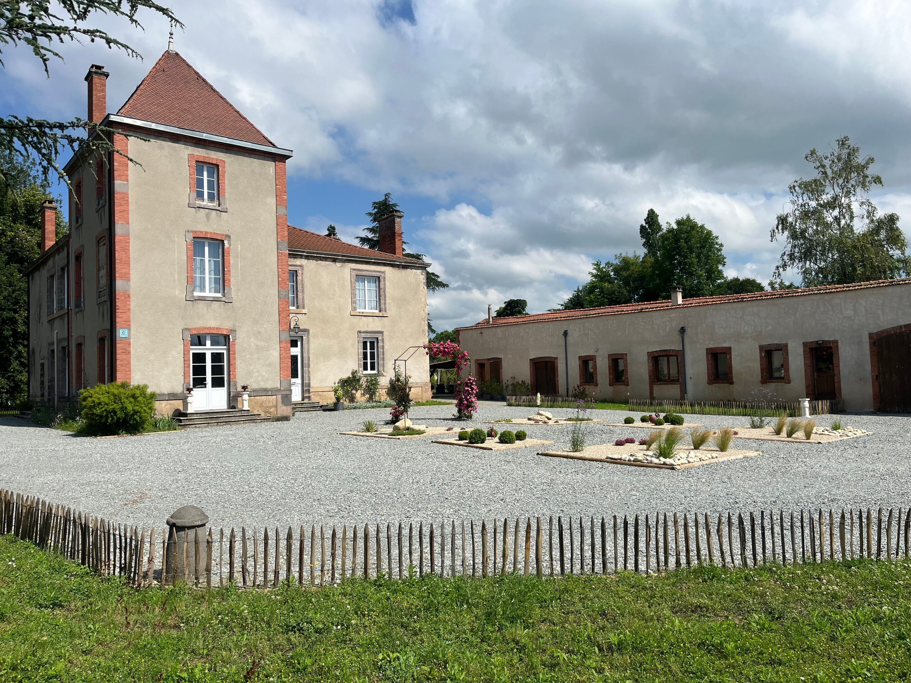 Een historisch gebouw met een binnentuin, een stenen hek en een grindpad.