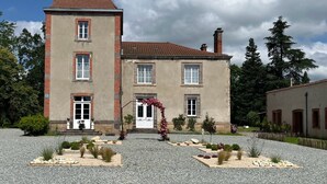 A two-story building with a central entrance, a tower-like structure on the left, and a gravel driveway. - Guest Room 4 with Shared Terrace, Wi-Fi and Air Conditioning (Joze)