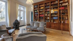 A spacious living room with a large bookshelf, comfortable seating, and a view through large windows. - Guest Room 4 with Shared Terrace, Wi-Fi and Air Conditioning (Joze)