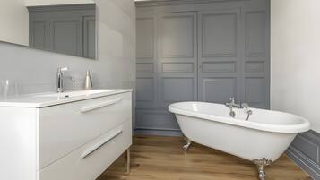 A bathroom with a white vanity, a freestanding bathtub, and a large mirror.
