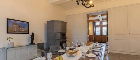 A dining room with a long table set for a meal, a fireplace, and a chandelier.