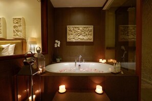 Une salle de bain moderne avec une baignoire sur pieds, des panneaux muraux décoratifs et des bougies.