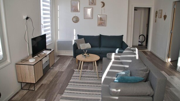 A living room with a sofa, a coffee table, a TV stand, and a wall with framed pictures.