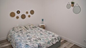 A bedroom with a floral bedspread, a bedside table with a lamp, and wall-mounted circular decorations.