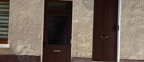 A building with two doors, a window, and a number sign.