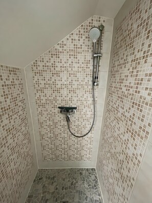 Une douche Ă©quipĂ©e dâun pommeau de douche Ă main et dâun robinet mural.