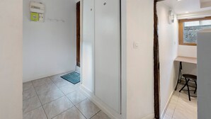 Un couloir avec une porte, un interrupteur et une fenêtre donnant sur un paysage.