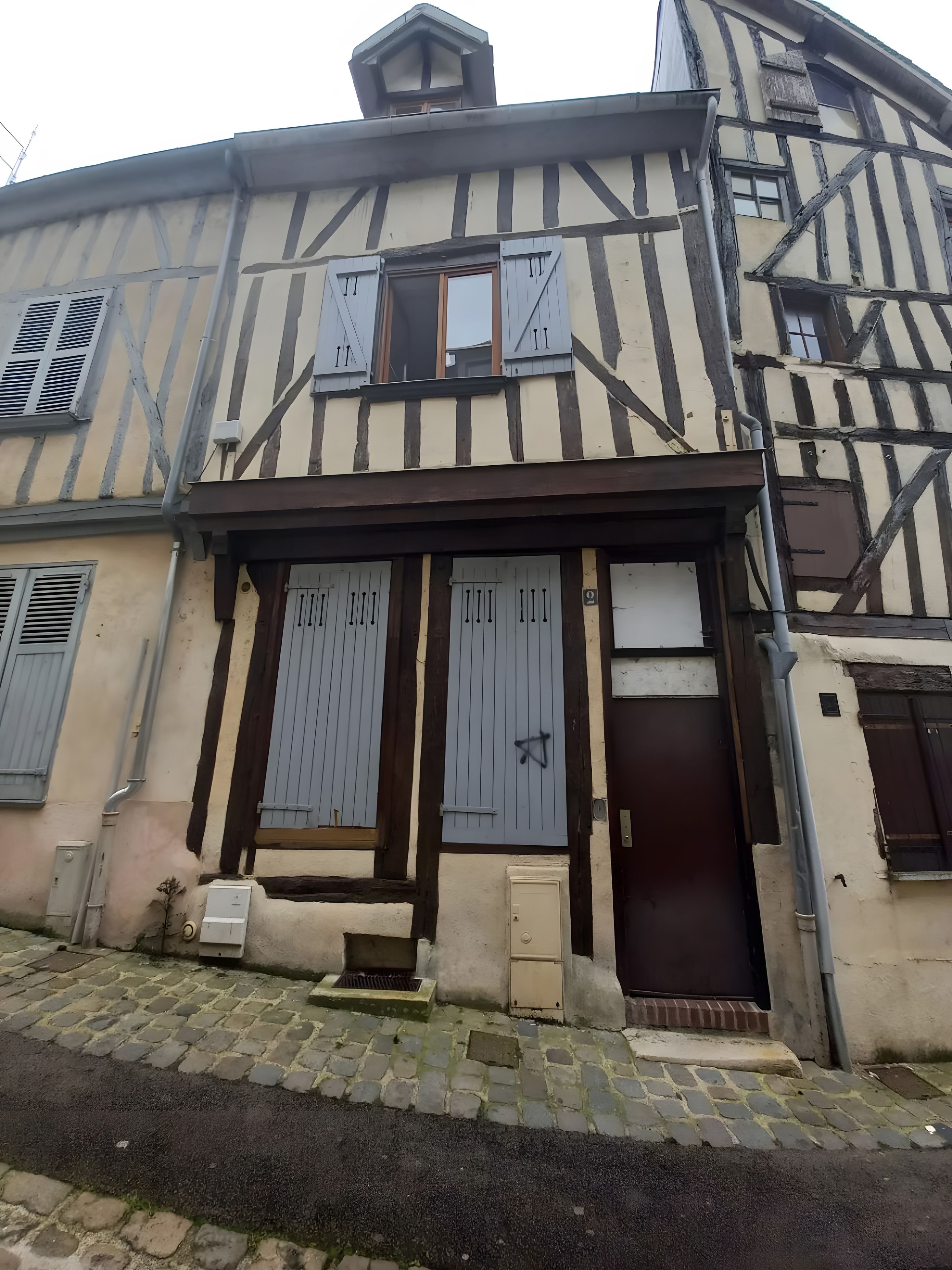 A traditional half-timbered building with a symmetrical facade, featuring two main doors and a small window above the central door.