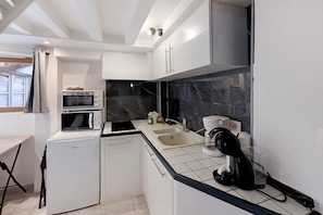 A compact kitchen with a built-in oven, a coffee machine, and a sink. - Apartment 'Logement Cosy Centre Joigny' with Wi-Fi (Joigny)