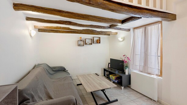 Un salon confortable avec un canapé, une table basse, un téléviseur et une fenêtre avec des rideaux.
