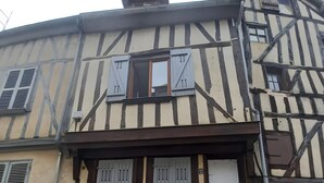 Un edificio tradicional con entramado de madera, fachada simétrica, múltiples ventanas y una entrada central con puerta.