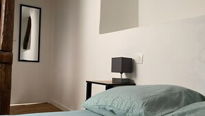 Un dormitorio con cama, mesita de noche, lámpara y un cuadro en la pared.