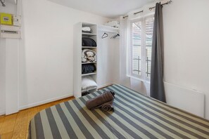 Un dormitorio con cama, armario y ventana.