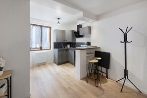 Eine moderne Küche mit grauen Schränken, einer schwarzen Arbeitsplatte und einer Bar mit Hockern.