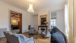 A spacious living room with a fireplace, a chandelier, and a large mirror.