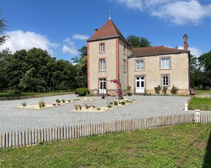 A two-story building with a red-tiled roof, a central entrance, and a gravel driveway.