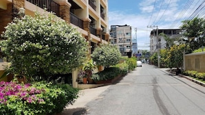 A residential street with a row of multi-story buildings, each with balconies and air conditioning units. - Jomtien Beach Residence (Pattaya)