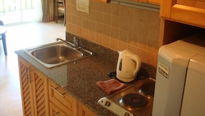 A kitchen with wooden cabinets, a stainless steel sink, a kettle, and a stove. - Jomtien Beach Residence (Pattaya)